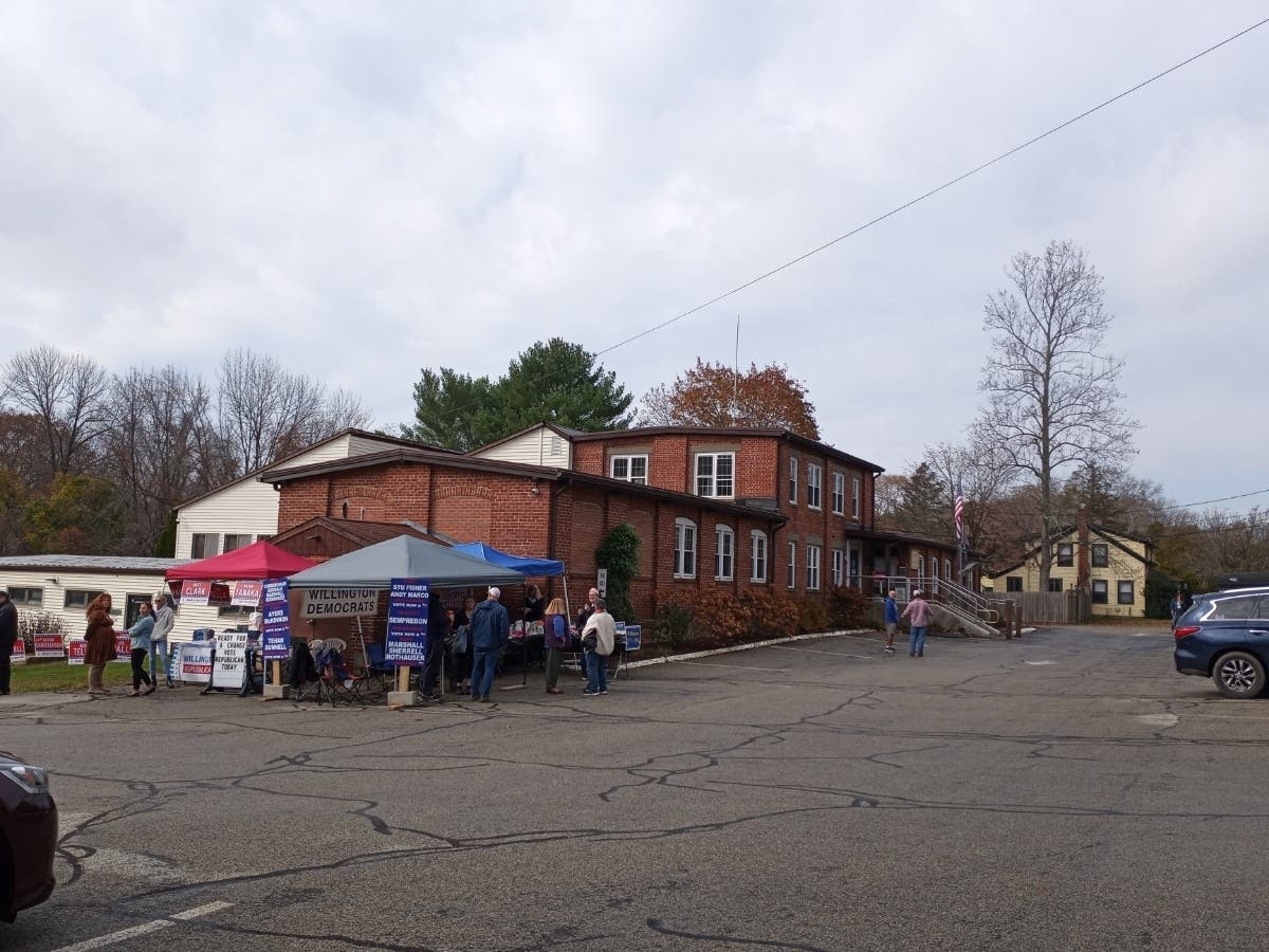 Archive photo: Willington’s Town Office Building during the November 7, 2023 municipal election. The campaign signs and people shown are from 2023, not the 2026 ballot.